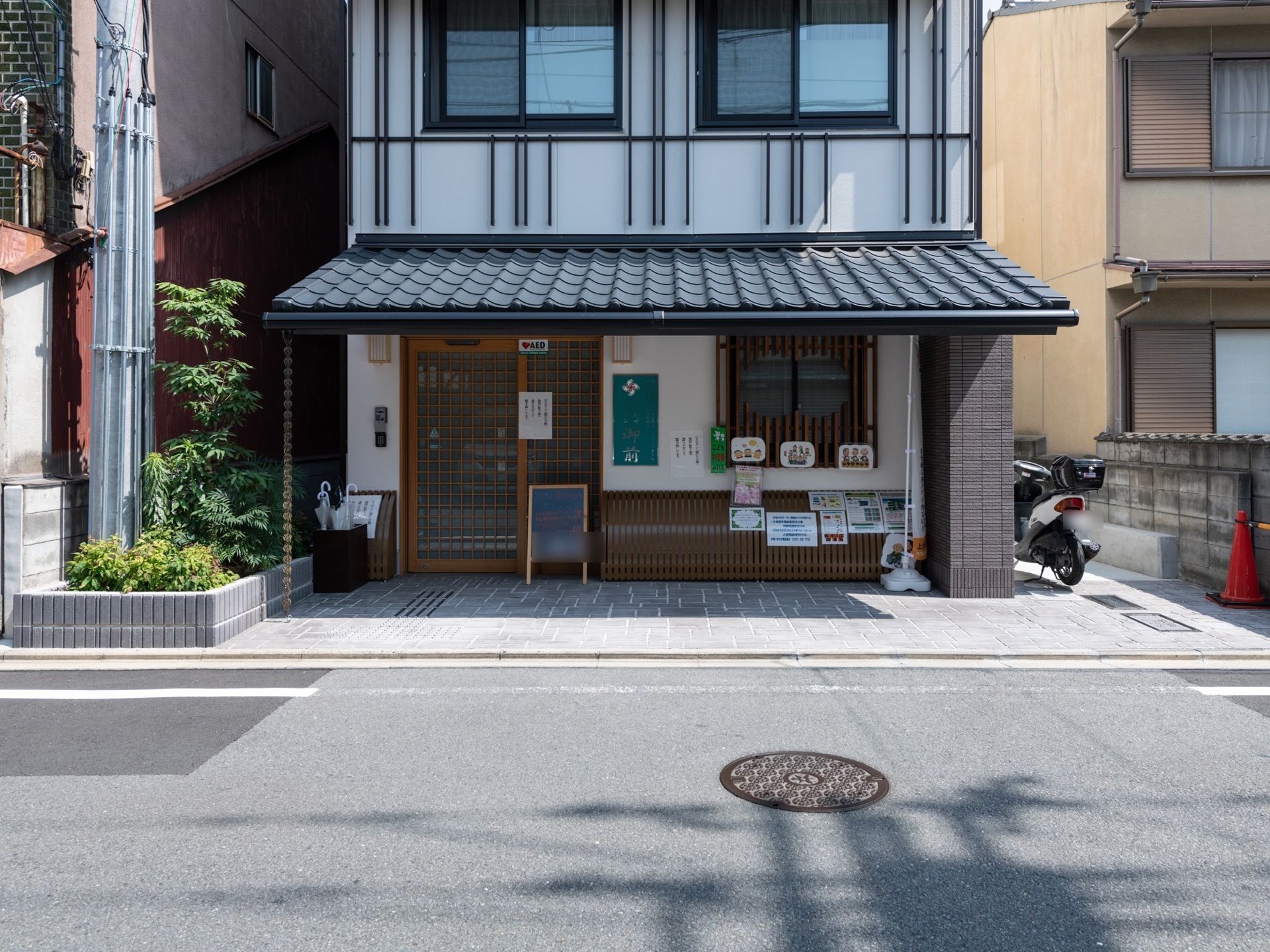 町家風の落ち着いた雰囲気の外観である。エントランスは広々としていて屋根が設けられているので、雨の日も快適に出入りできる。