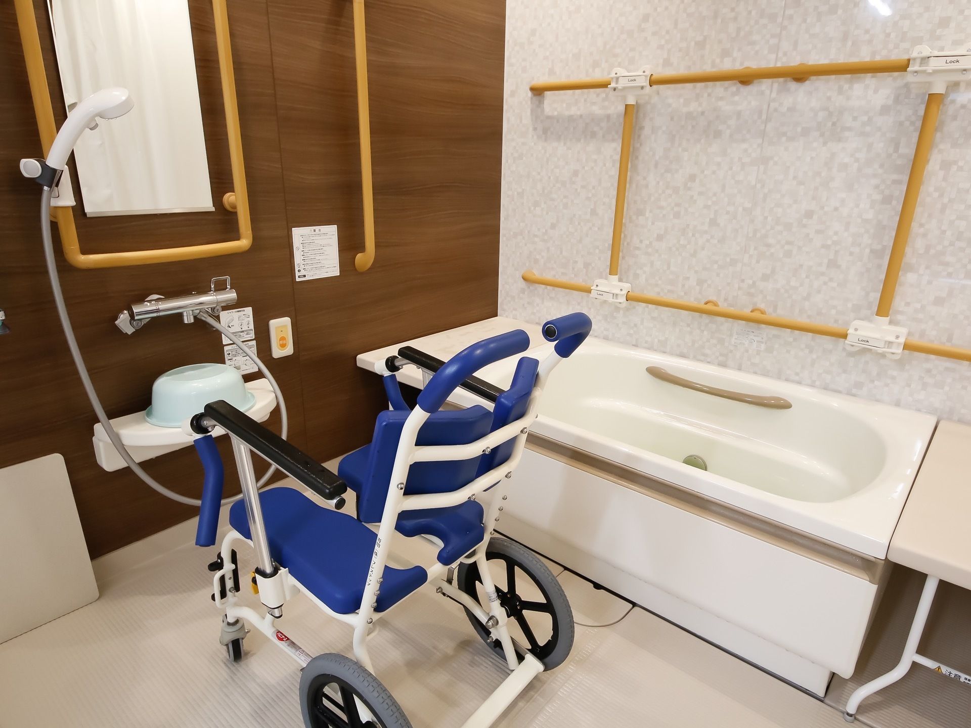 入浴用の車椅子やバスボードが用意され、壁や浴槽のいたるところに手すりがついている。入浴介助に必要なものは一通りそろっている様子である。