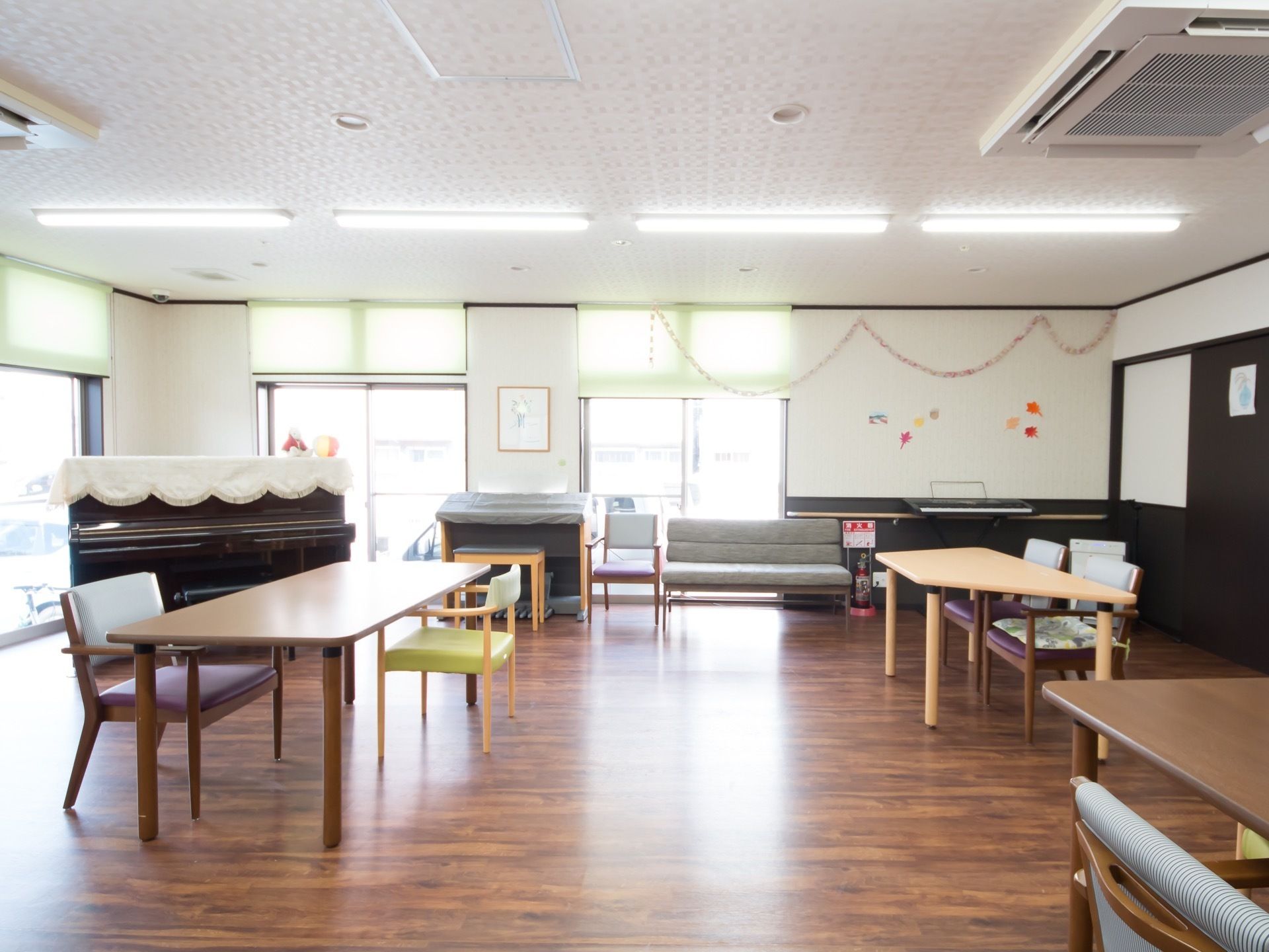 高さのある窓が複数並んでおり、明るく広々とした部屋である。家具と家具との間隔を充分に確保して配置している。