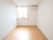 白い壁とベージュのフローリングで明るい部屋である。窓辺の淡いピンク色のカーテンが、部屋のやわらかい雰囲気を引き立てている。