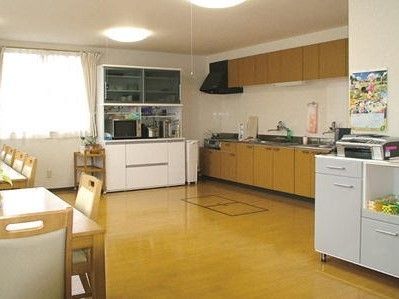 薬を飲む高齢女性と水を差し出す女性スタッフ