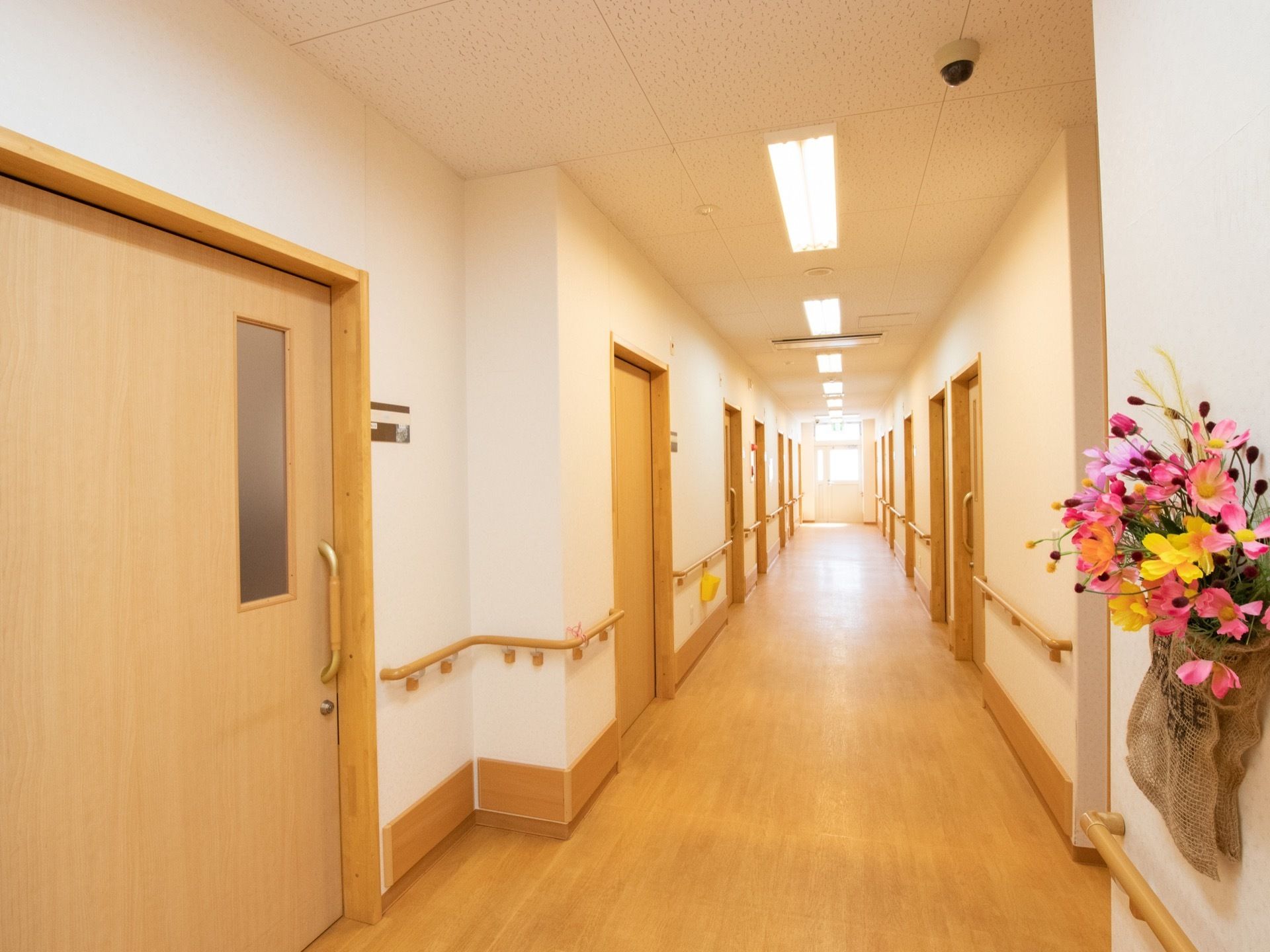 廊下には居室の扉が並んでおり、大きなスライド式で、楽に開閉することができる。壁に花が飾られており、華やかである。