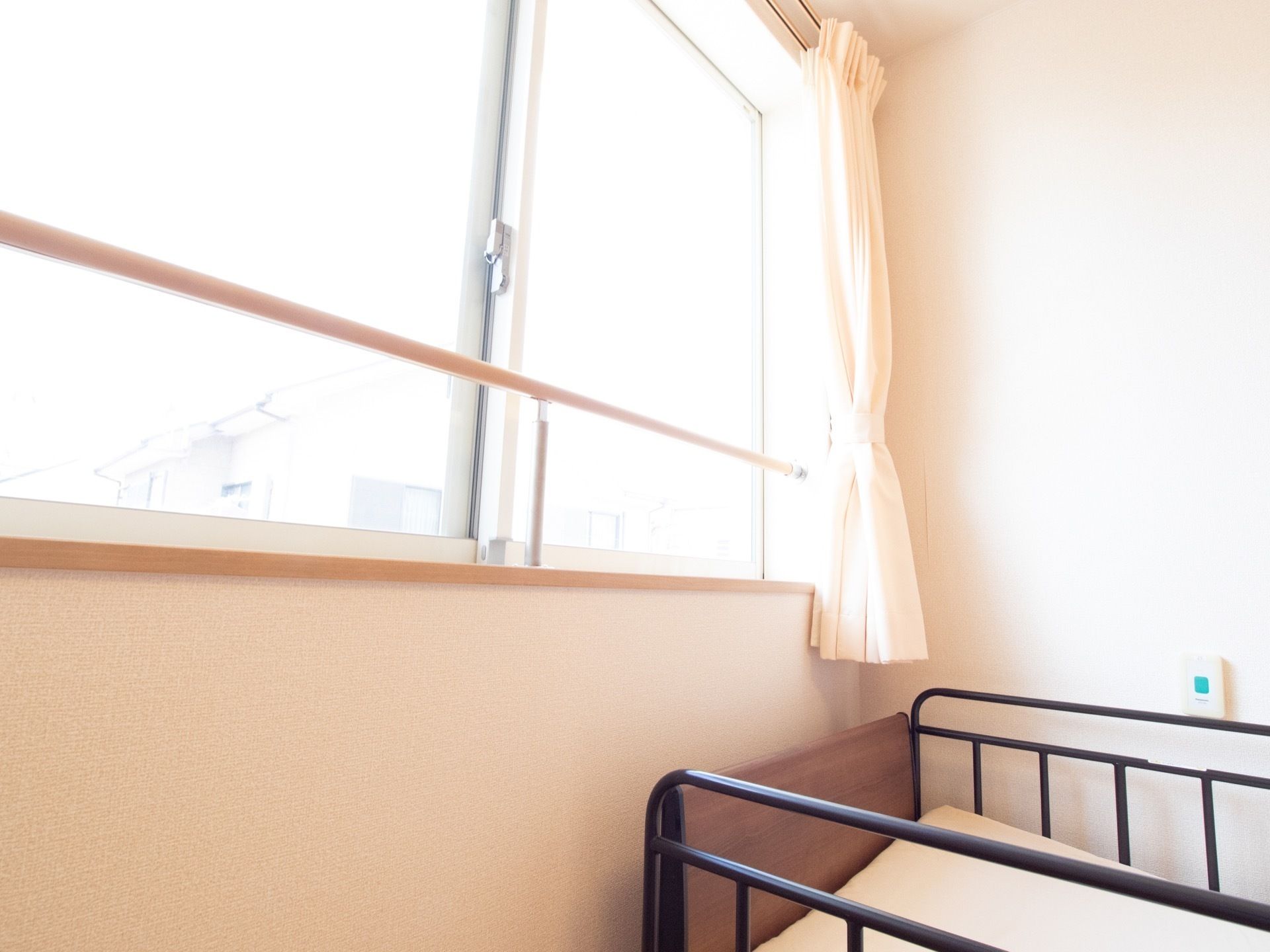 引違い窓付近に補助手すりを設けた、明るいカラーの居室