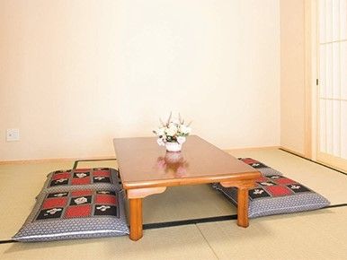 畳の部屋にローテーブルと座布団が置かれている。テーブルの上には花瓶が飾られている。