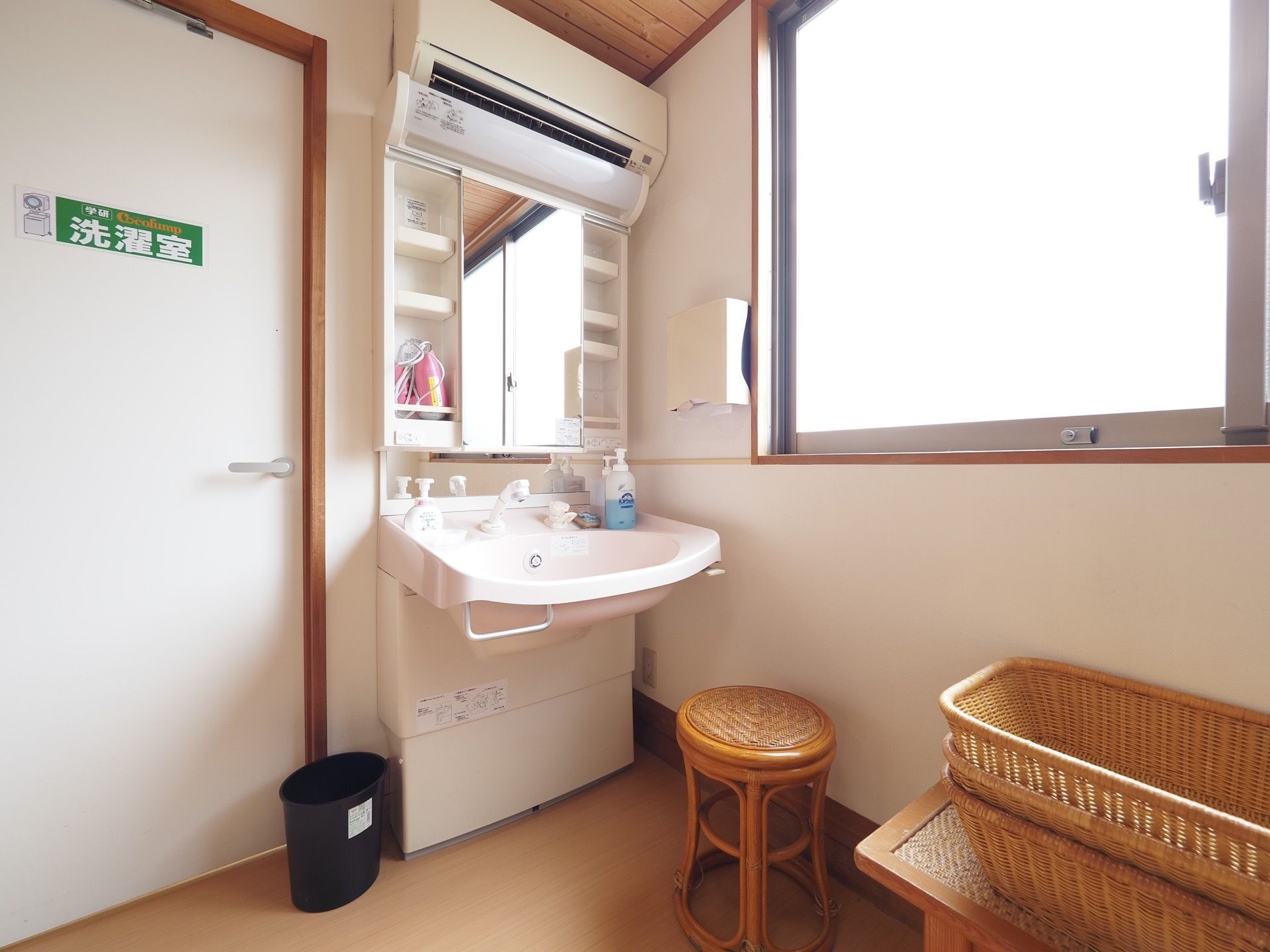 洗濯室前の洗面台である。シャワー水栓が付いている。足元はすっきりとしており、鏡の横に収納スペースがある。