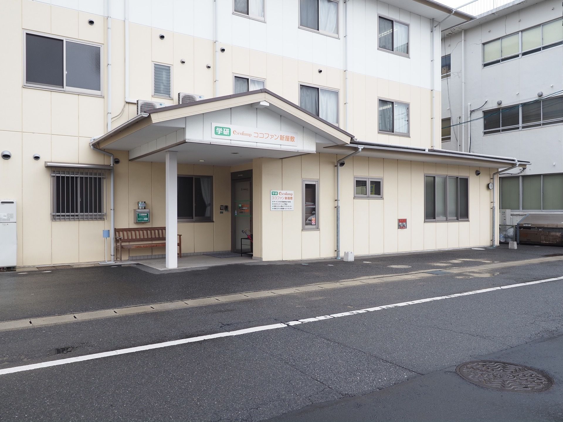 玄関には木製のベンチが1台置かれており、上部には大きなひさしが設けられている。ひさしの部分に施設名が書かれている。
