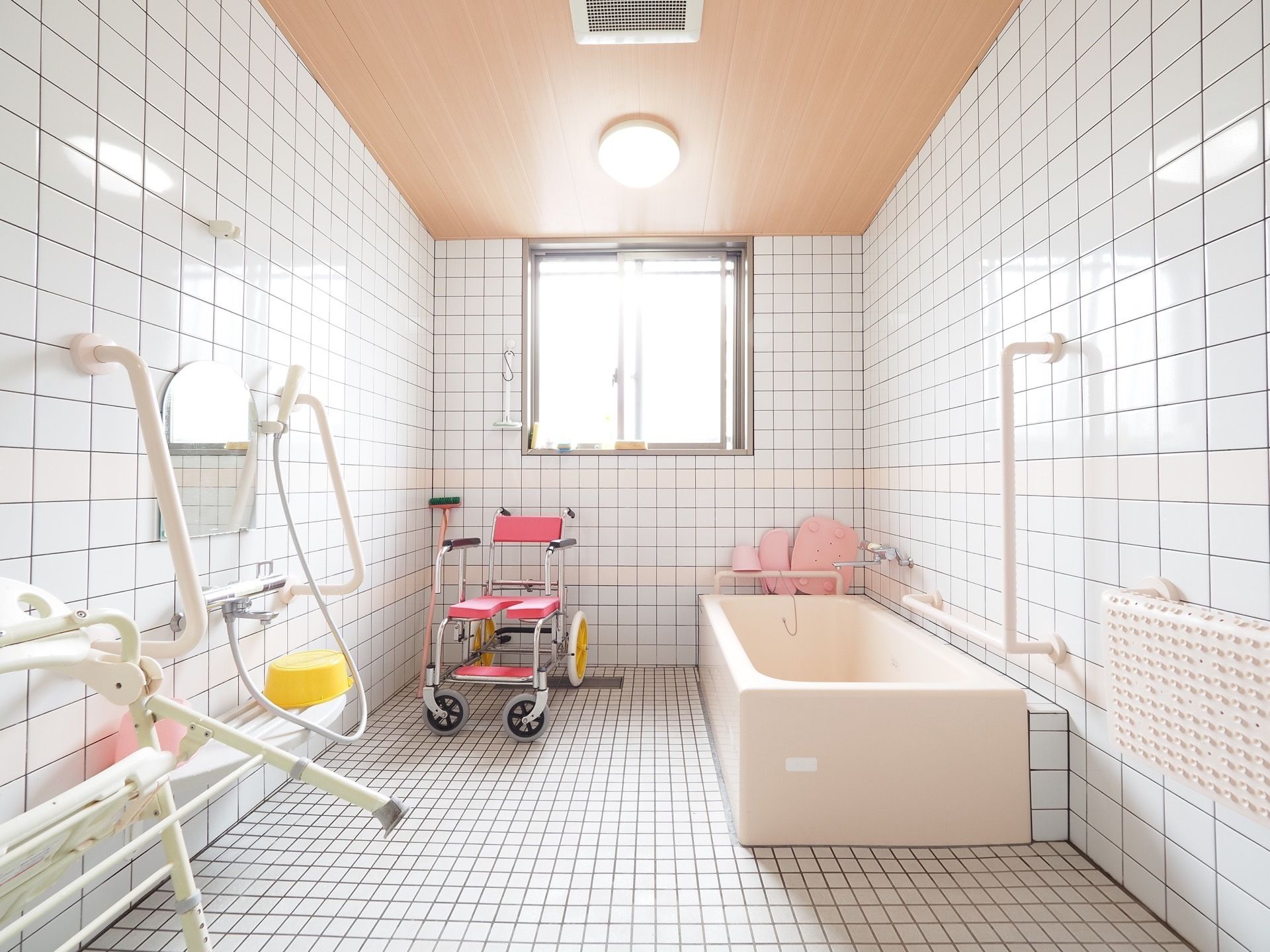 洗い場には鏡が取り付けられており、その両側に手すりが設置されている。壁側に掃除道具が綺麗に並べて置かれている。