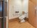 居室のトイレは空間にゆとりがあり、ドアも大きい。便器には背もたれがついており、壁には手すりとナースコールが設置されている。