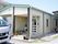 三角屋根の１階建ての建物である。玄関前の壁際に花の鉢やプランターを飾っている。反対の横側にはスロープを設置している。