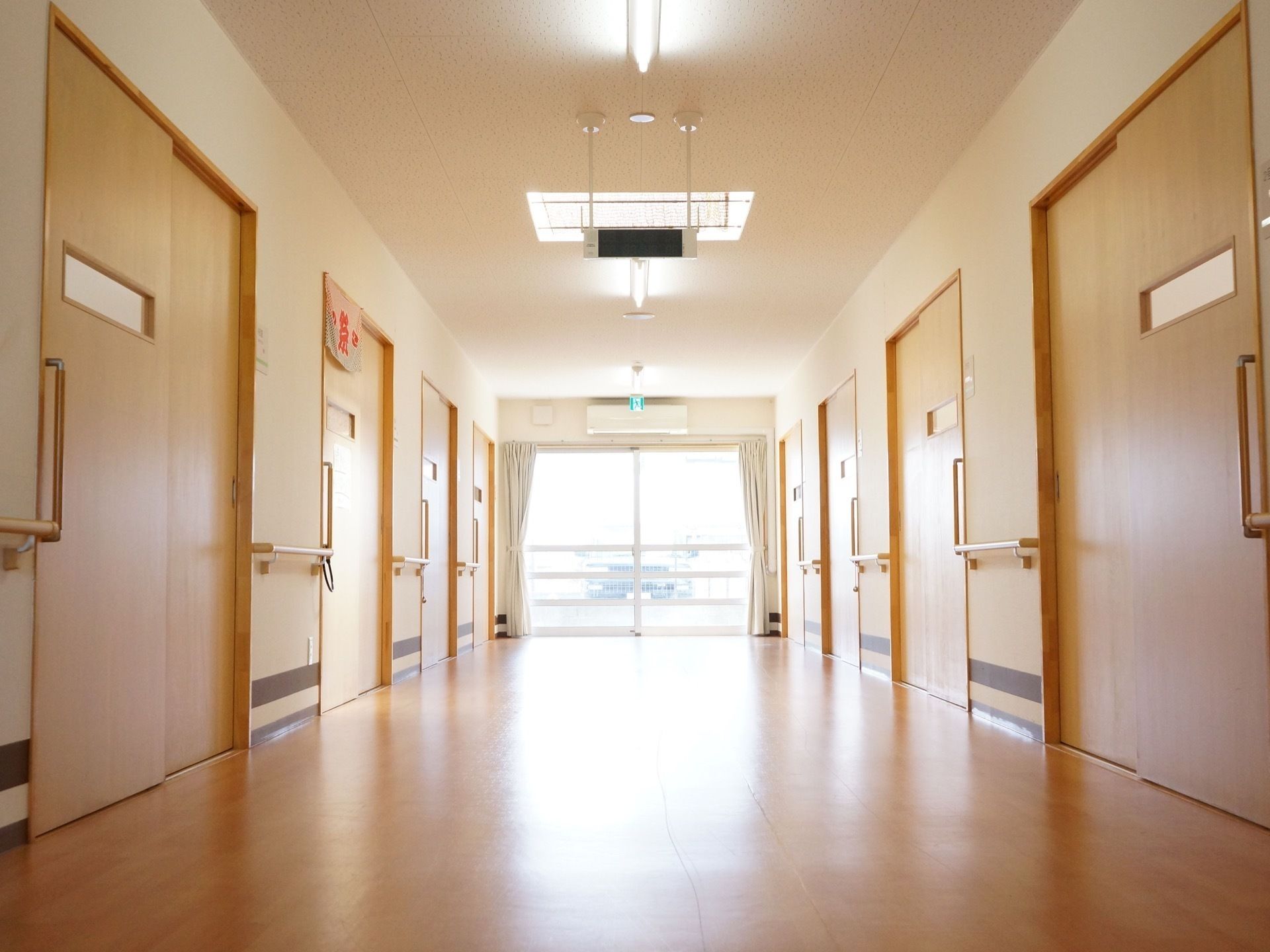 スライド式のドアがあり、その間の壁に手すりを設けた居住空間の廊下