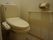 白を基調としたトイレスペースである。便器横の壁に手すり、トイレットペーパーホルダーなどを完備している。
