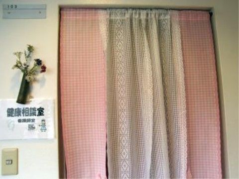 通路の壁に小さなイラストと健康相談室と書かれた紙が貼られている。その下には電気スイッチが設置されている。