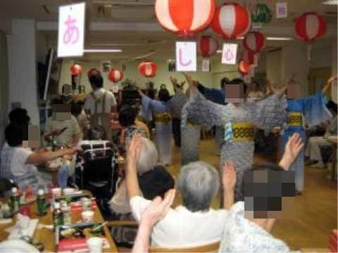 お祭りの様子。浴衣を着た女性が広間で踊っている。椅子に座りながら踊りを楽しむ入居者様もたくさんいる。
