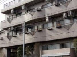 ブラウンを基調としたマンションのような外観のグループホームである。道路に沿って花壇が設置されている。