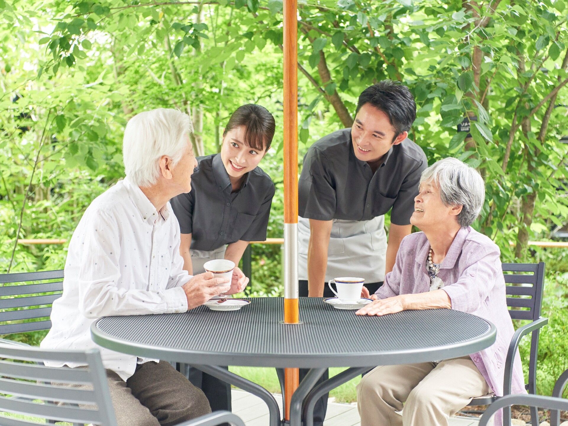 女性スタッフが高齢者に何かを話しかけている様子。お互いに目を見て微笑んでいる