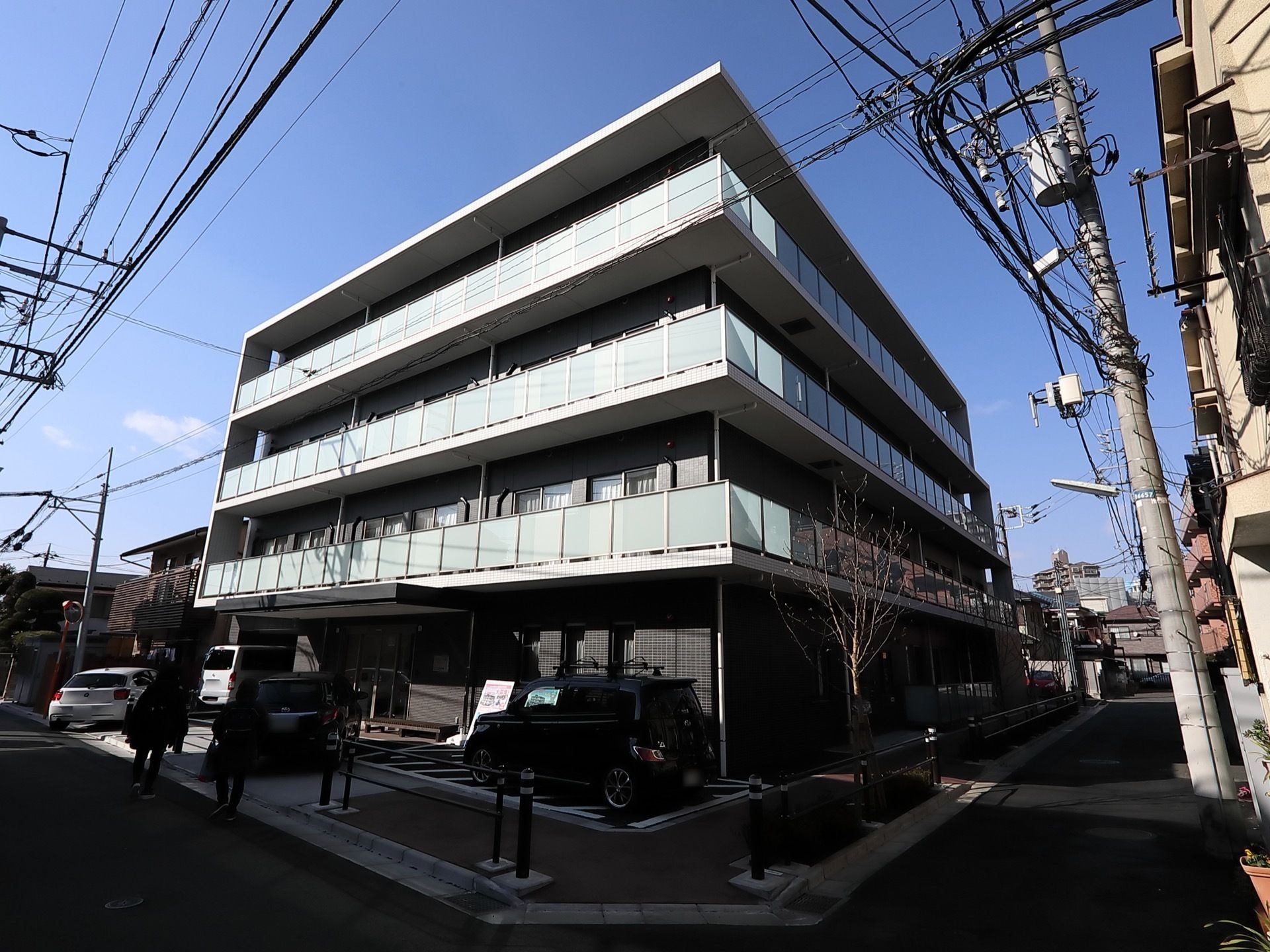 ダークカラーでまとめられた4階建ての建物。1階部分には駐車スペースもある。