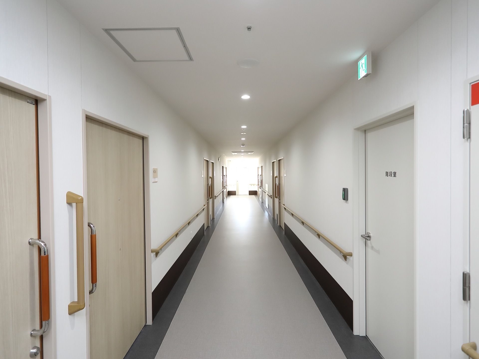 手すりを壁全面に設置した廊下になっている。居室の扉はスライド式になっており、安全に開け閉めすることができる。