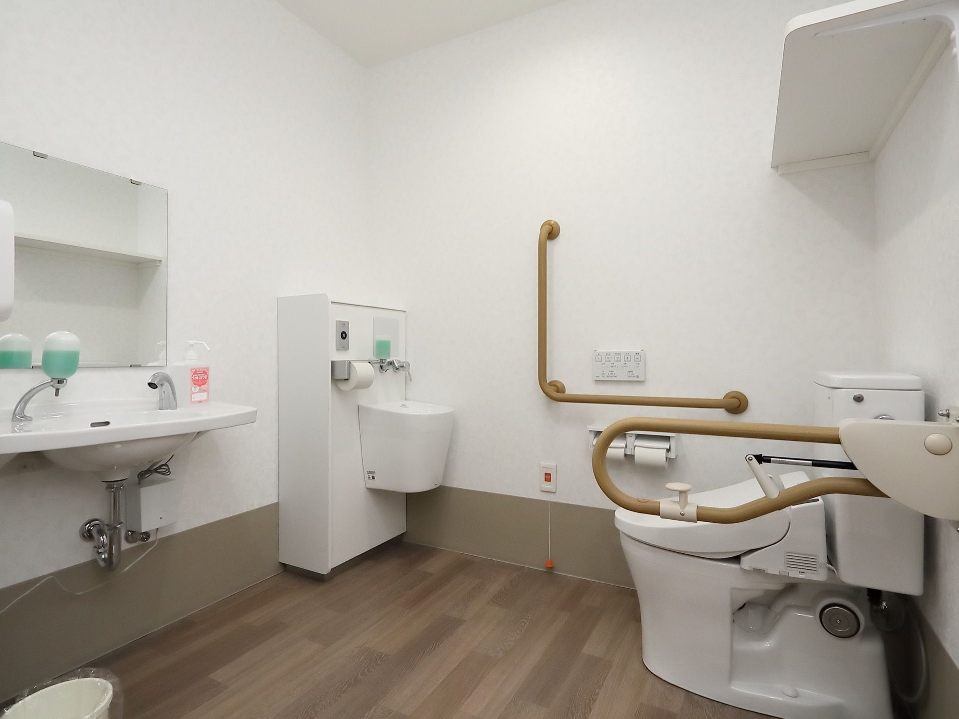 広いスペースを確保したオストメイト対応のトイレである。手すりがL字型に設置されており、立ち上がる際に体を支えることができる。