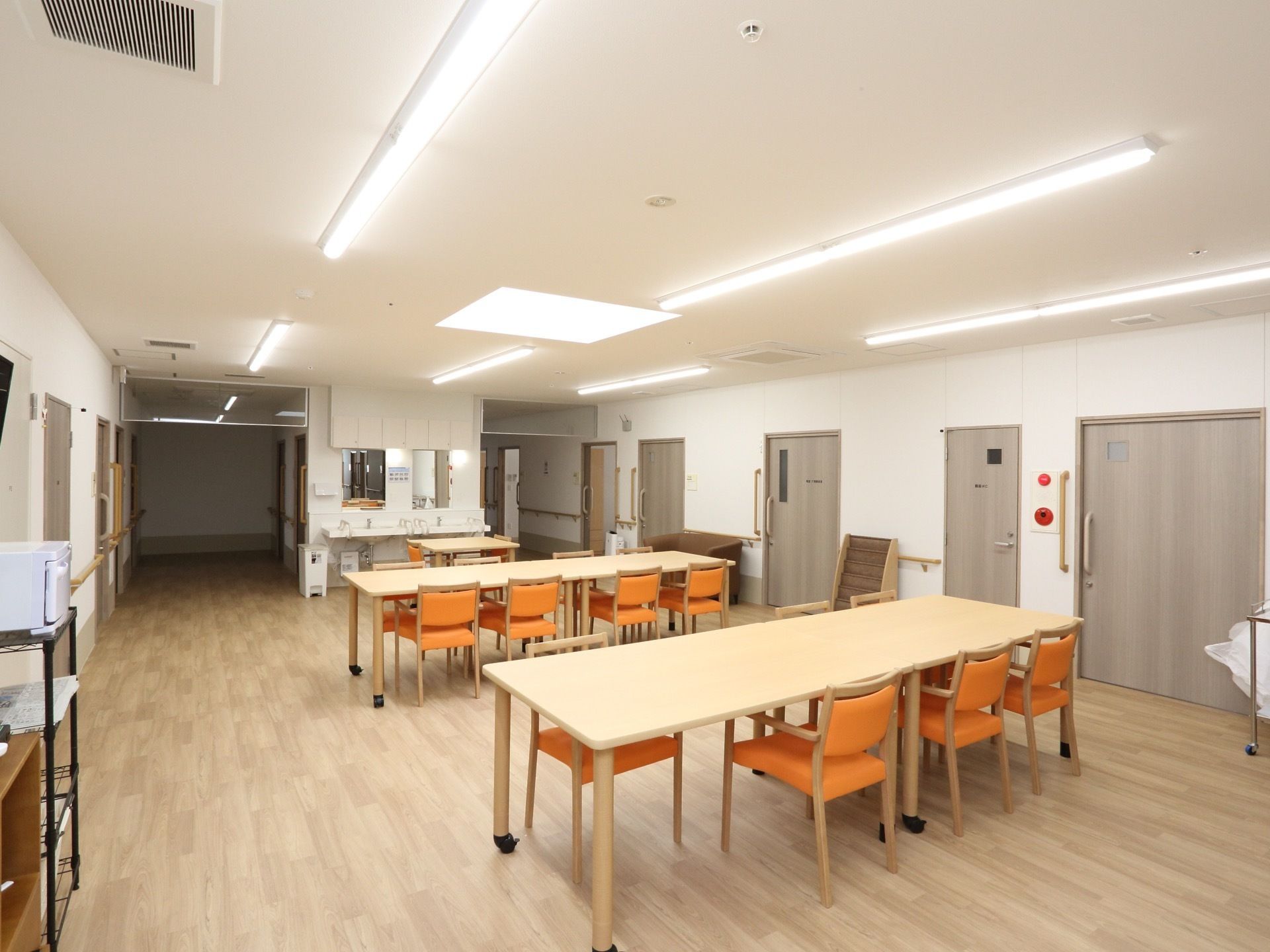 食堂には木製のテーブル、背もたれとひじ掛け付きの椅子が複数用意されている。洗面台や電子レンジもある。