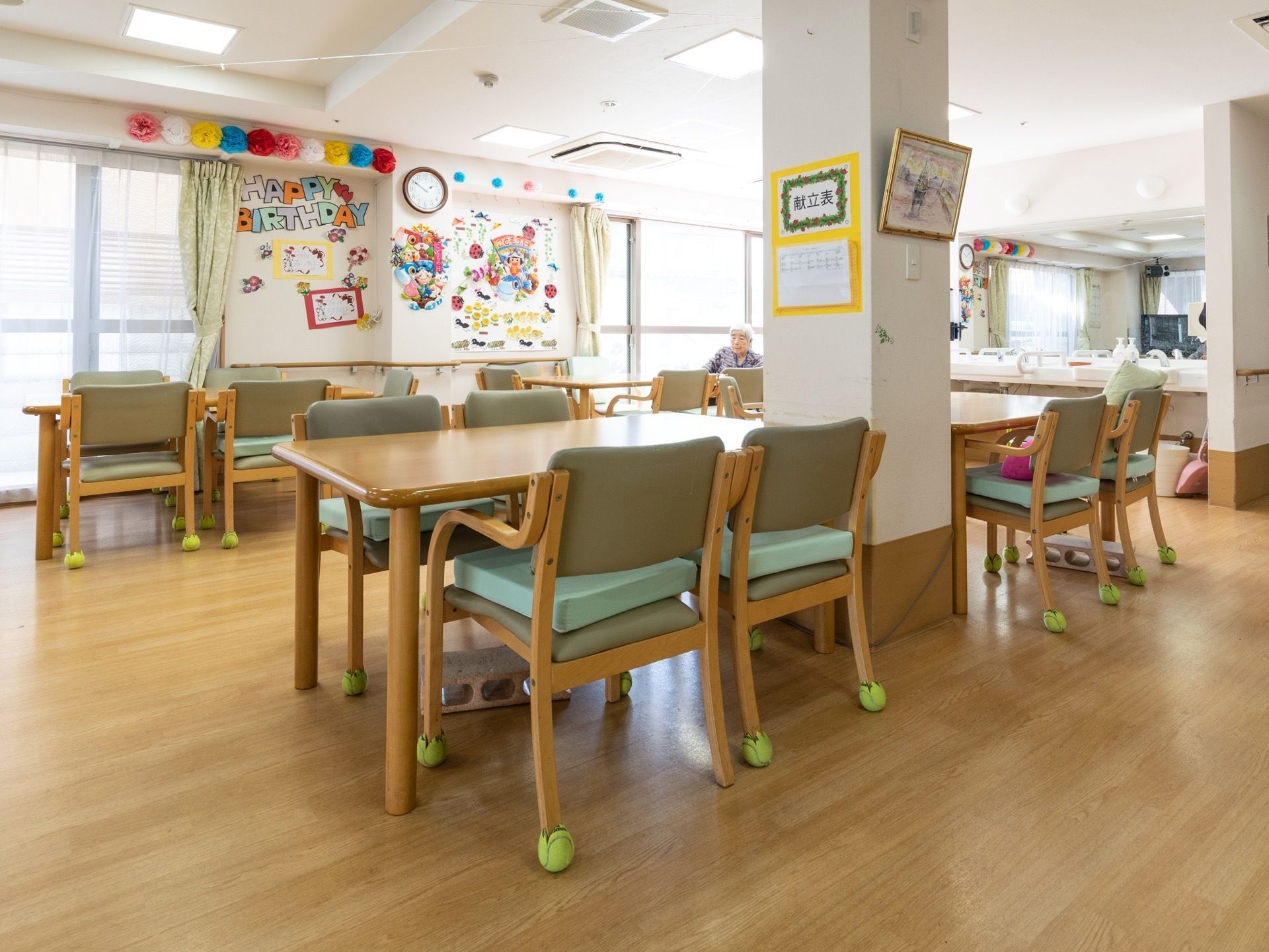 複数のテーブルと椅子が設置されている。壁には献立表や、色とりどりの装飾が施されており、窓も大きいため明るい印象の食堂となっている。