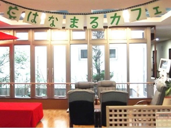 ゆったりと座れるリクライニングチェアのような椅子が４脚置かれている。左には茶屋のような赤い縁台があり、赤い傘が差してある。