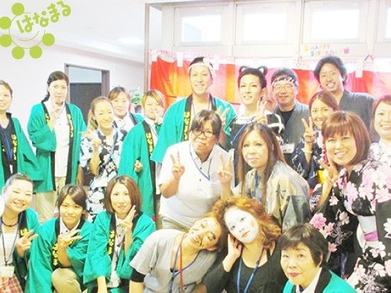 はっぴや浴衣を着たり、仮装をしたスタッフが大勢写っている。笑顔でピースサインをしていて、仲の良さを感じられる。