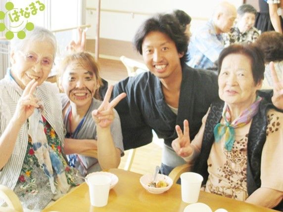 入居者様とスタッフが楽しそうにピースサインをしている。テーブルの上には食べ物や飲み物が置かれている。