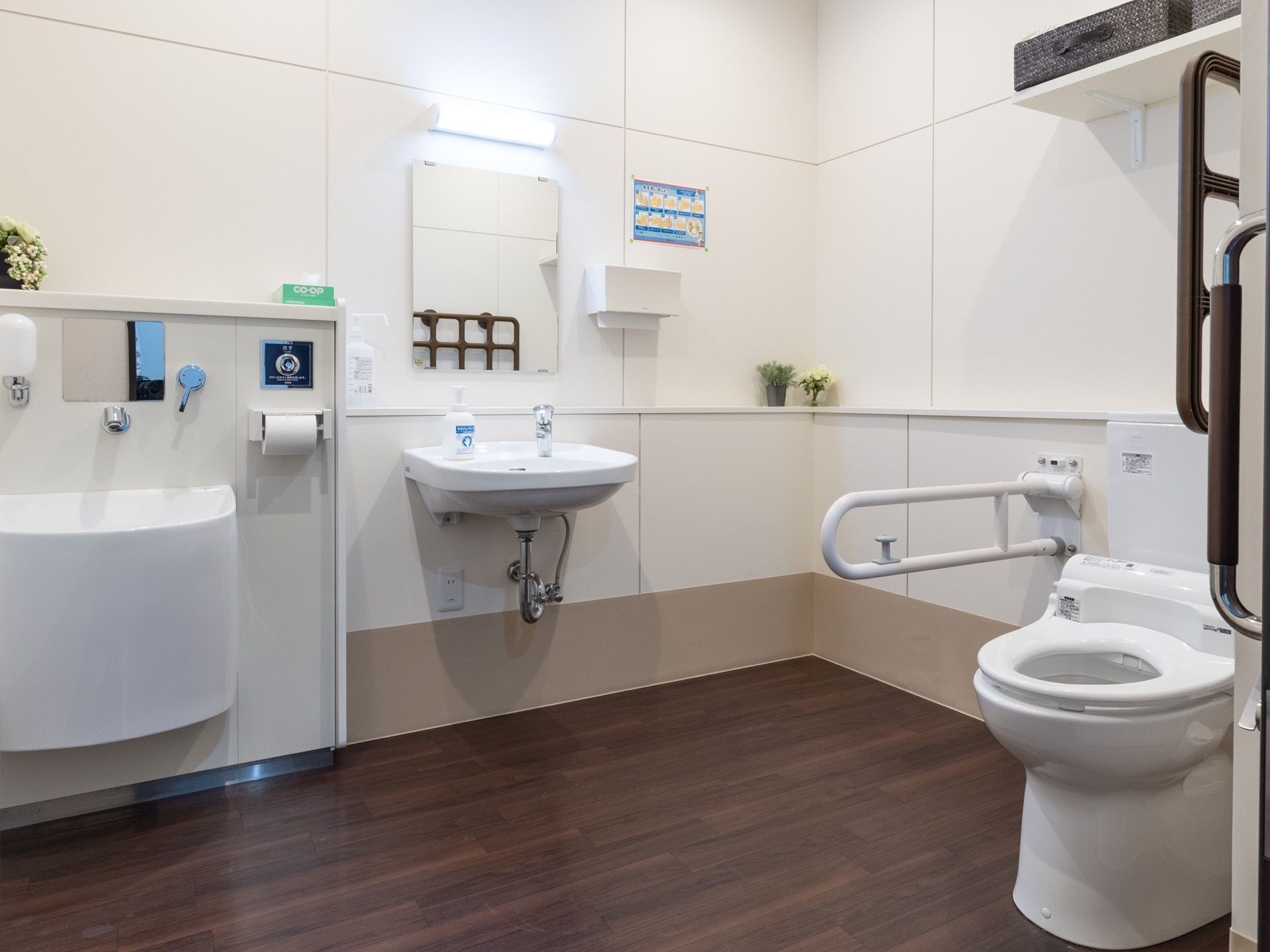 トイレのそばには手すりが取り付けられている。すぐそばに洗面台と汚物流しが設置されている。ペーパータオルも用意されている。