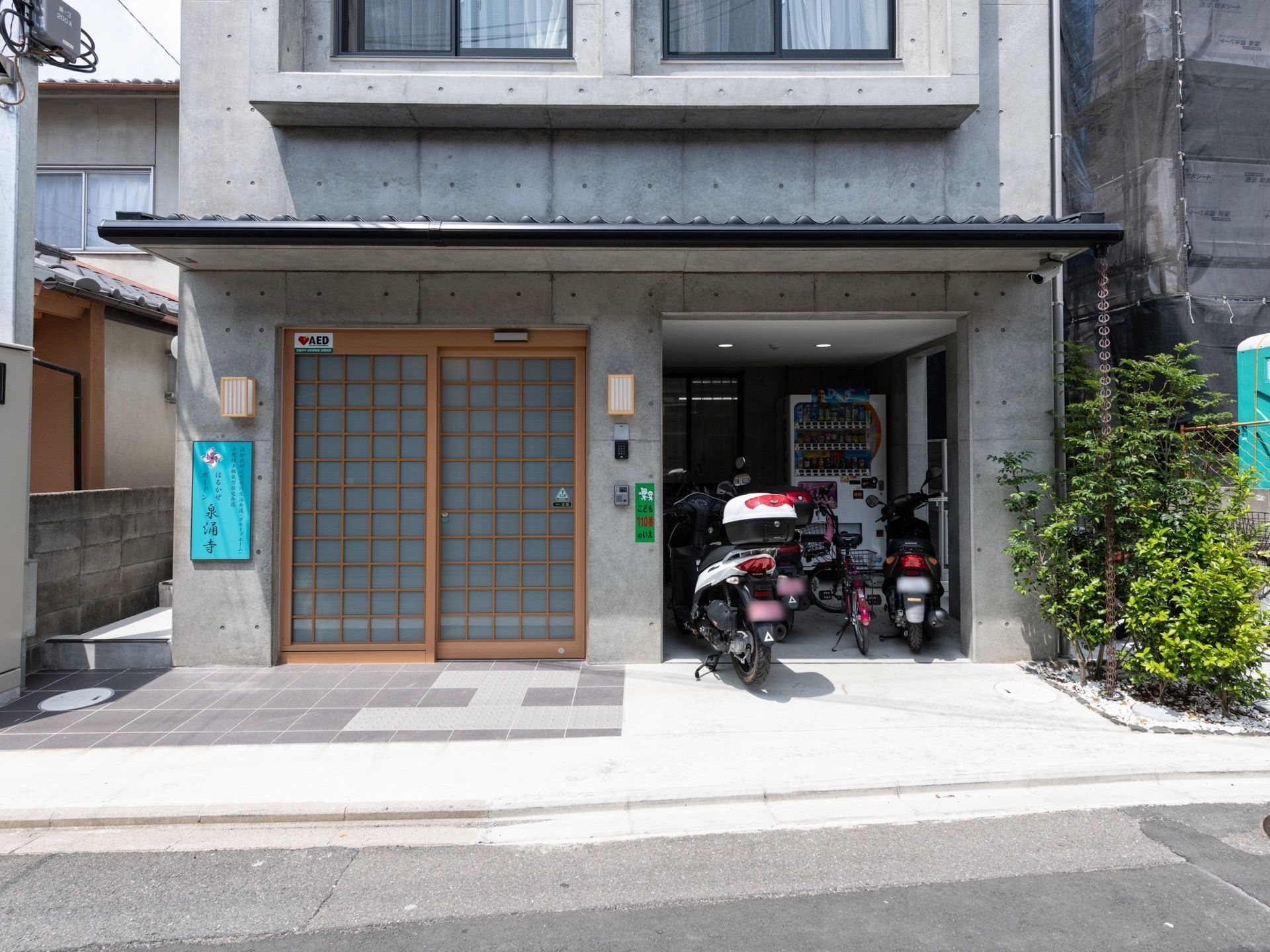 駐車スペースを設けた、コンクリート壁のモダンな雰囲気の施設の玄関