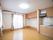 収納のついたキッチンと温熱調理台のついた部屋がある。2面に窓があり、壁にはエアコンが設置されている。