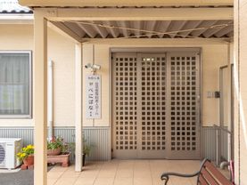 施設の入り口はブラウンのステンレス製の格子戸になっている。入り口前には屋根が設置されており、ベンチが置かれている。