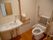 背もたれや可動式の肘置きが設置されたトイレと、鏡を設けた手洗い台
