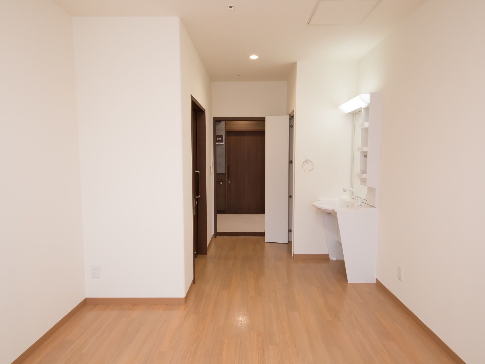 白と茶色で構成された内装の部屋である。出入り口は引き戸である。手洗いスペースがあり、その横にタオルハンガーが取り付けてある。