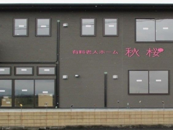 施設の建物の外観である。壁の色はグレー系で、窓が多く設置されている。壁面には施設名がピンク色で表示されている。
