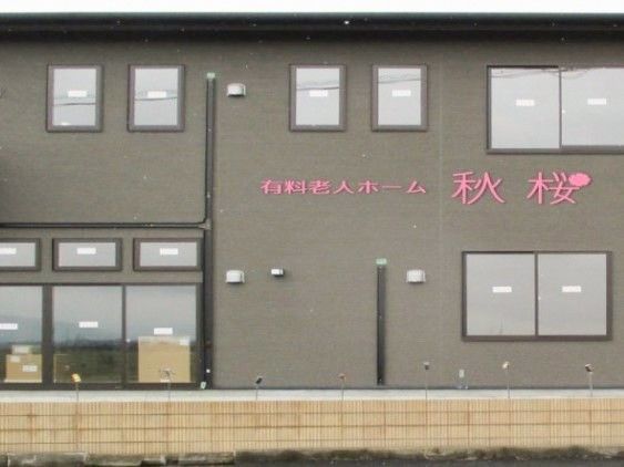 黒い外壁にパッションピンク色の文字看板を取り付けた施設外観