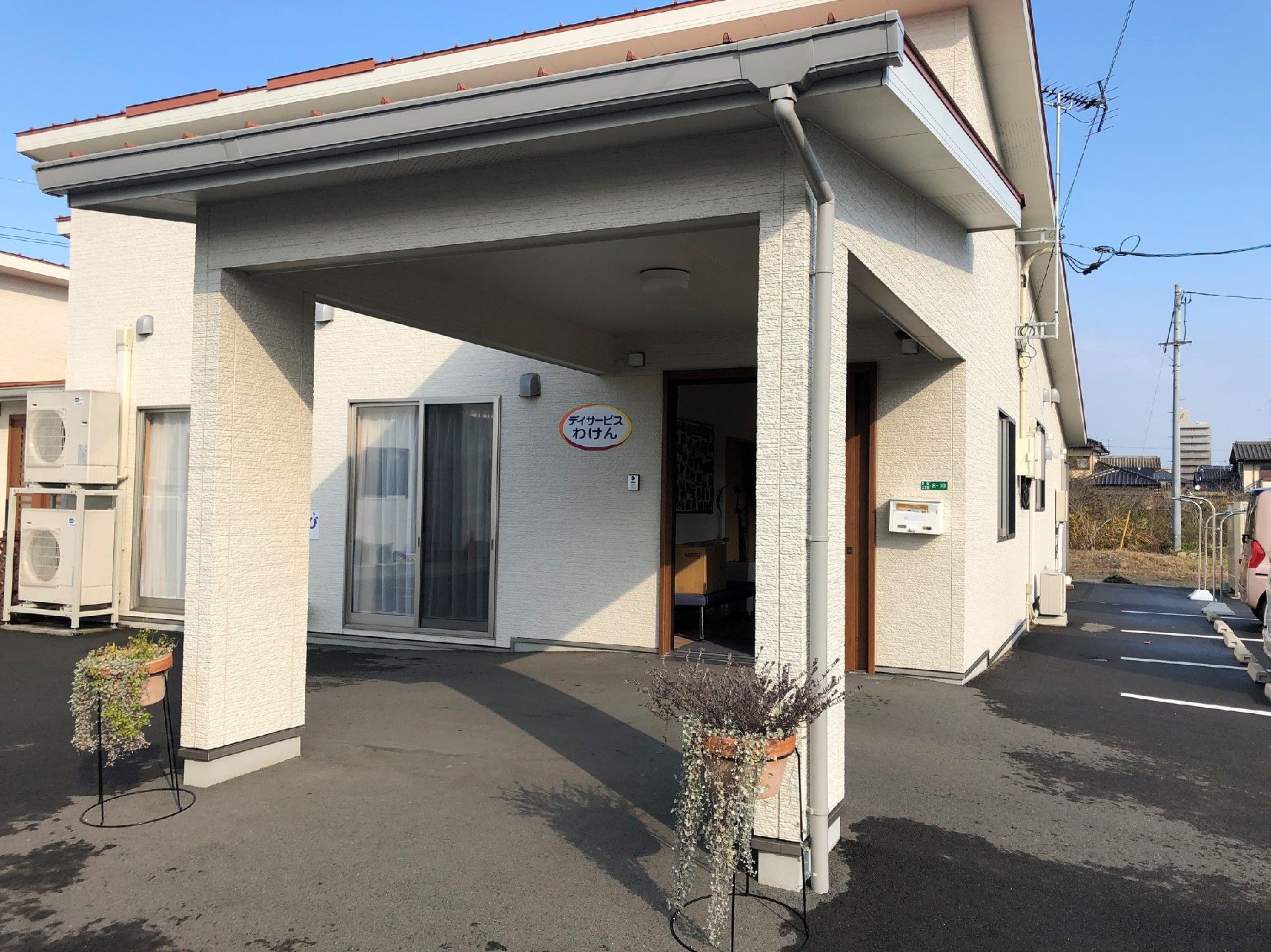 白い壁の一軒家で、スライド式の玄関になっている。内側から出入りが可能な大きな窓が付いているので開放感がある。