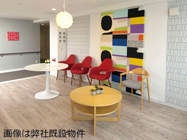 鮮やかな色合いのタペストリーが架かる、明るく広い室内。赤い椅子やデザイン性が高い照明もあり、インテリアに拘っている。