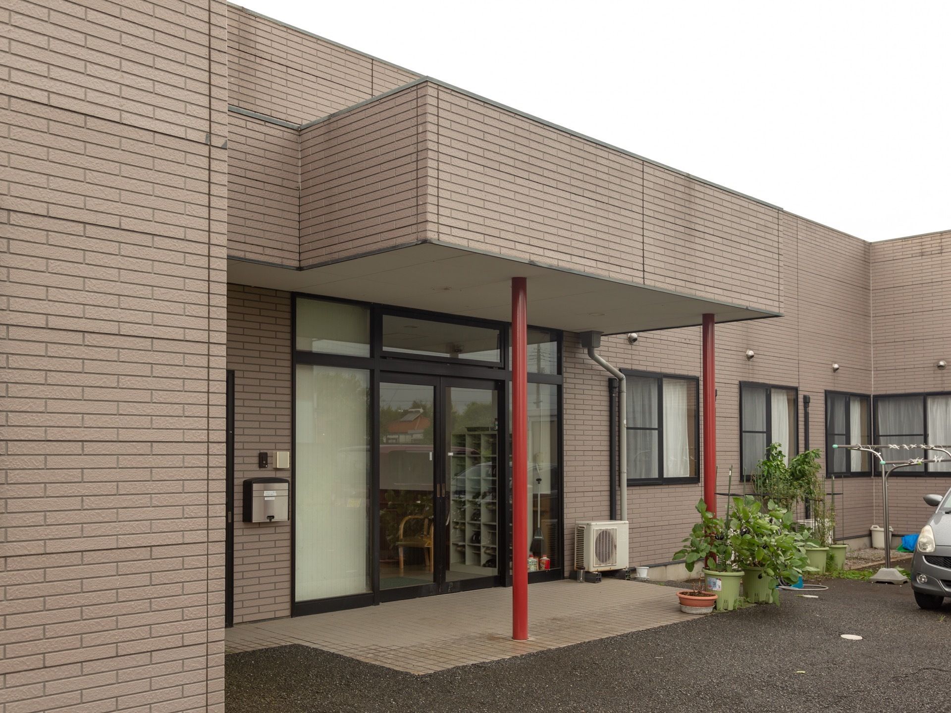 物干し竿が外にあり、玄関にはインターホンがある。玄関を入ると靴入れと椅子がある。広々とした自然に囲まれてのびのびと生活できる。