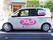 駐車場に施設所有の白い２ドアの乗用車が停められている。助手席側のドアには、大きく施設名が書かれている。