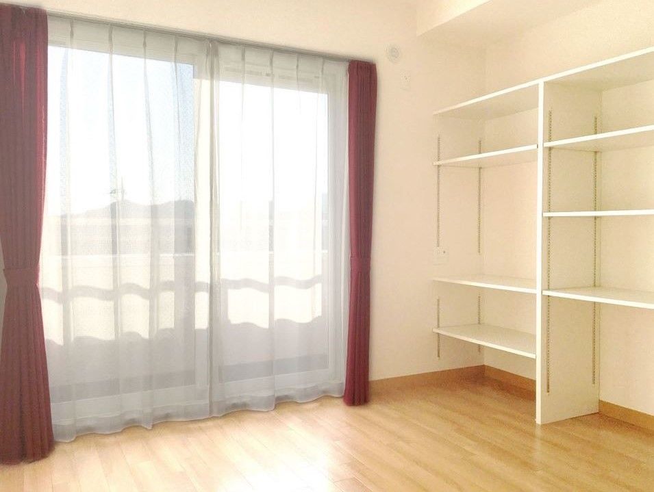 壁面には造り付けの白い棚があり、棚の幅を変えて活用できる。窓は大きく、光を取り込み明るい環境で過ごせる。