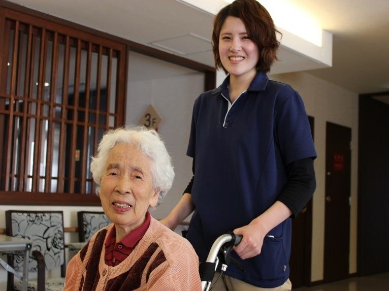 館内を車椅子で移動する入居者様に、スタッフが付き添っている。散歩や買い物などに同行するサービスもある。