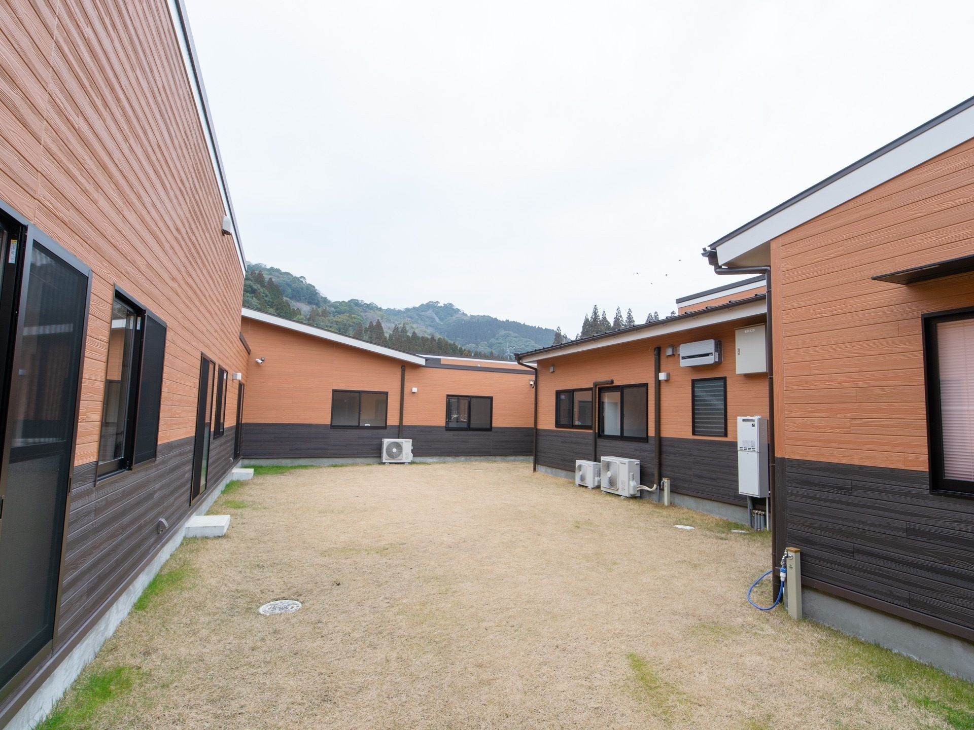 木造の平屋建てで、茶色のツートンカラーである。奥に山が見える。視界を遮る大きな建造物がなく、広々とした空を眺めることができる。