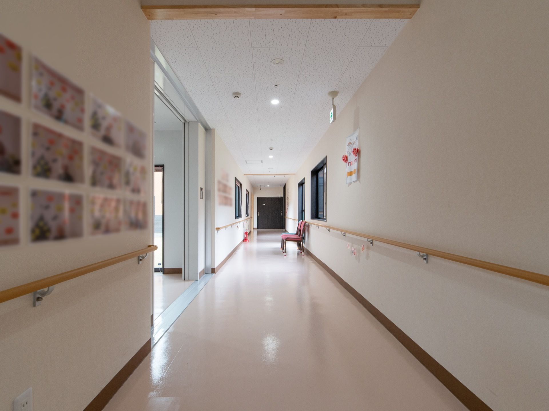 段差もなく広々としている。壁には写真や手作りの作品が飾られている。消火器や椅子が置かれている。手すりが備わっている。