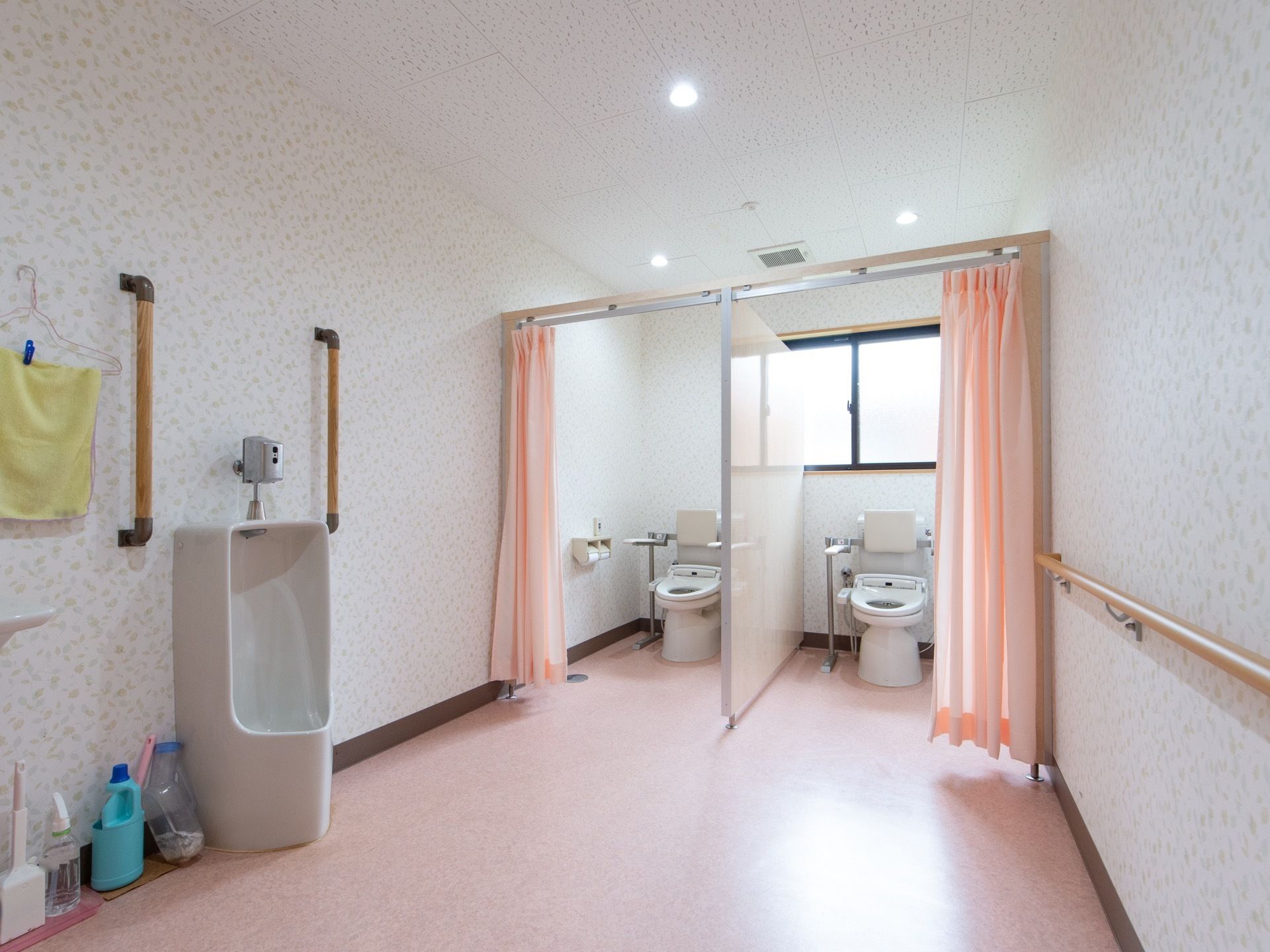 男性用便器と洋式トイレが備わっている。それぞれに手すりが設置されており、洋式トイレには背もたれも用意されている。