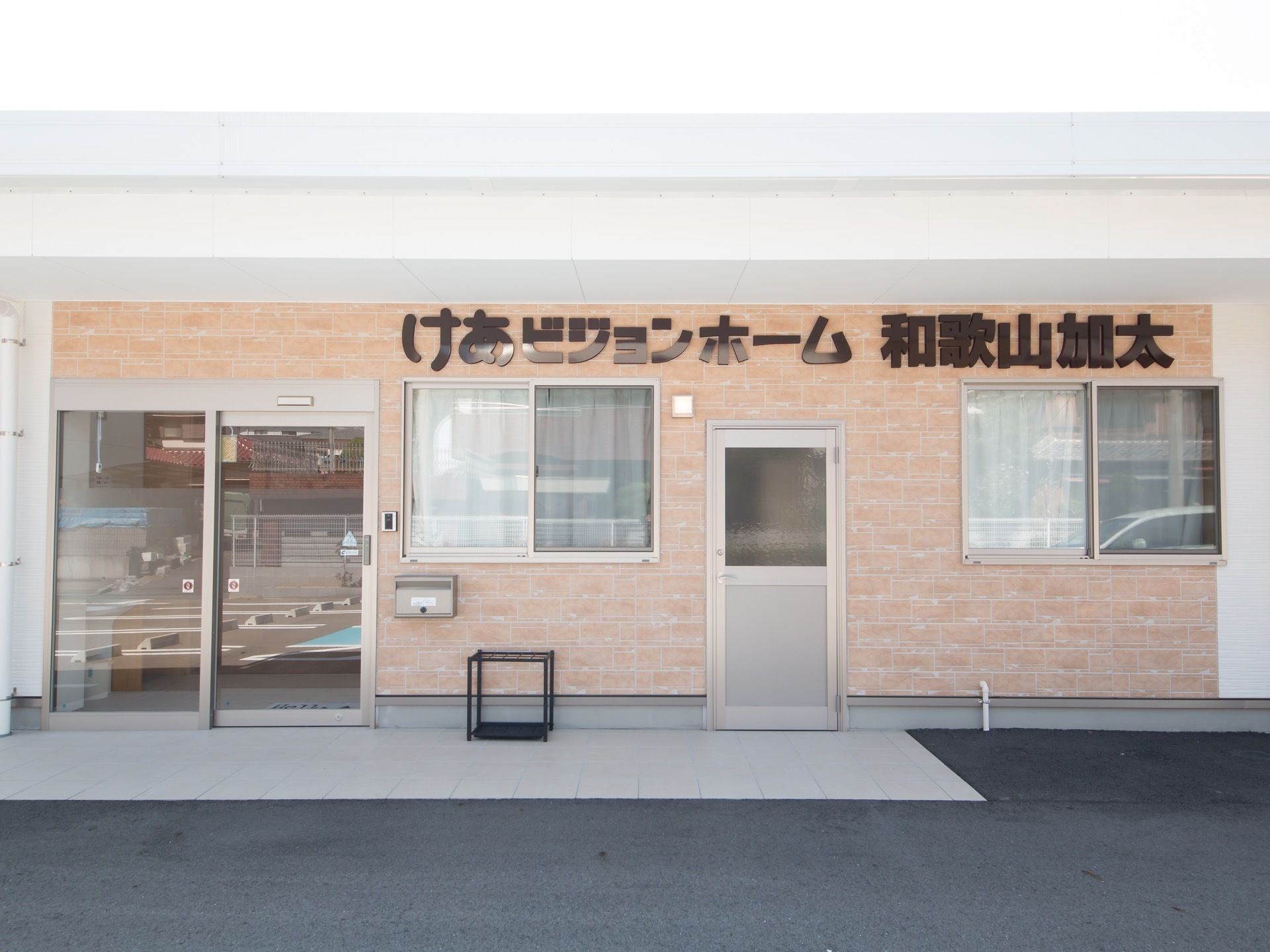 段差のないフラットなエントランスである。長方形のひさしがもうけられている。自動ドアが玄関扉に採用されている。