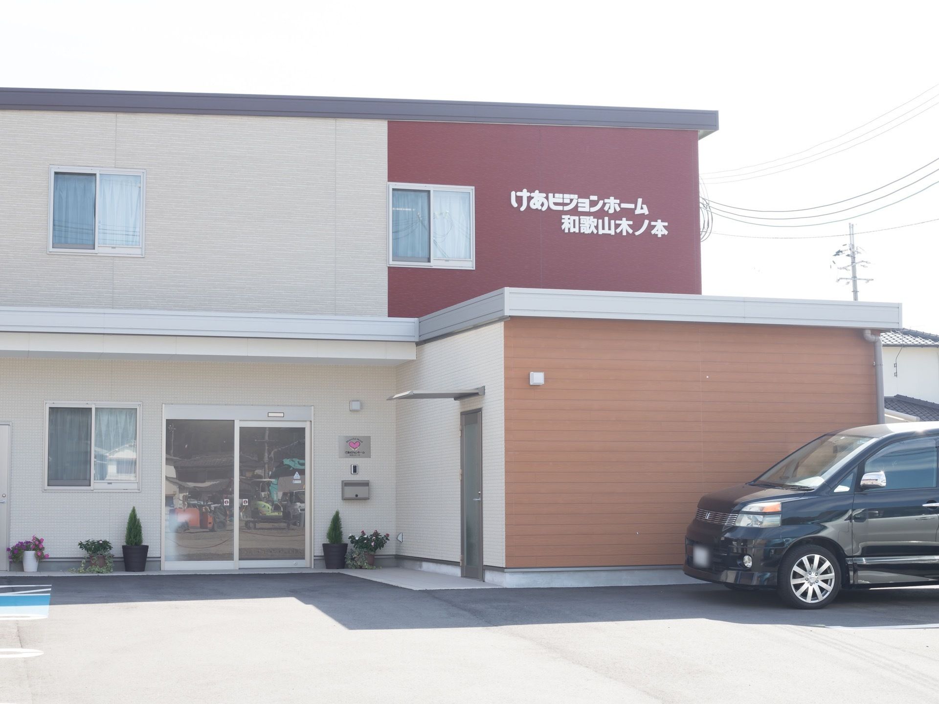 スッキリとした外観の２階建ての施設である。出入口には、自動ドアが設置されている。壁際に観葉植物が置かれている。
