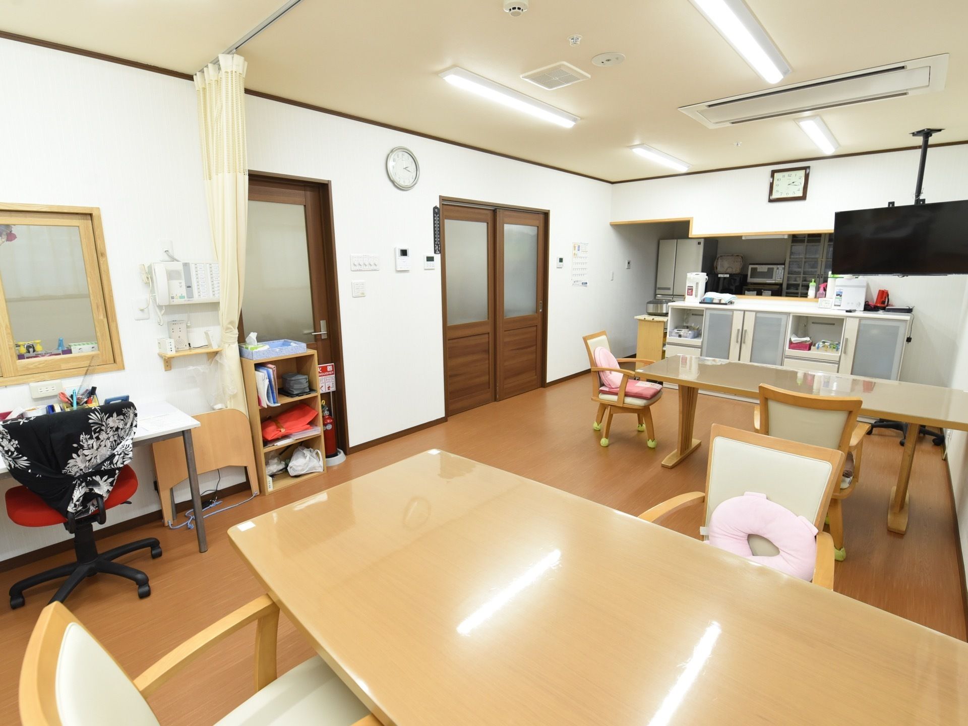 キッチンのあるお部屋に、食器棚を挟んでダイニングテーブルを並べている。白いシートの椅子には、肘掛がある。