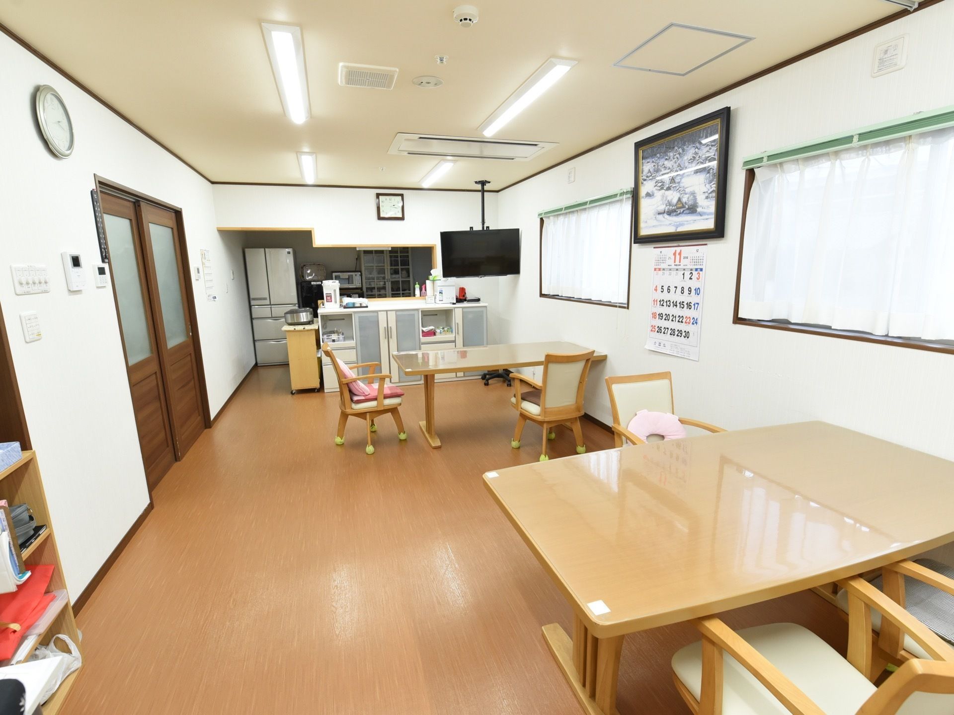 ダイニングルームのテレビは天井からぶら下げて取りつけてある。エアコンは天井に埋め込んでいる。顔の高さに窓が２セットある。