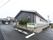 黒い一階建ての建物。入り口に屋根がついており、上に施設名が書かれている。駐車場が広く用意されている。