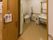 施設内の男女兼用トイレである。段差のない広いスペースがあり、便器と手洗い洗面台、手すり、鏡、ゴミ箱が用意されている。